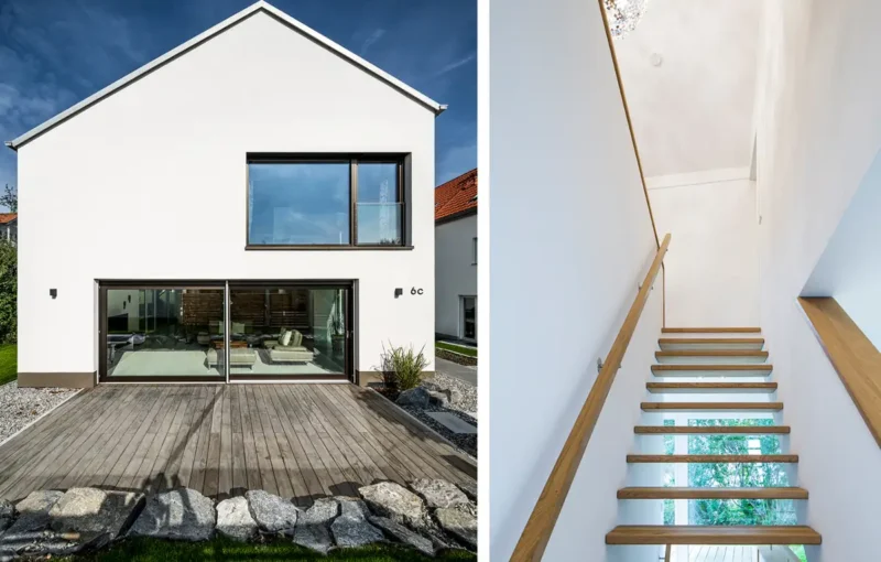 Modernes weißes Haus von außen mit großen Fenstern und Glastüren und einer Holztreppe mit Glasgeländer im Inneren.