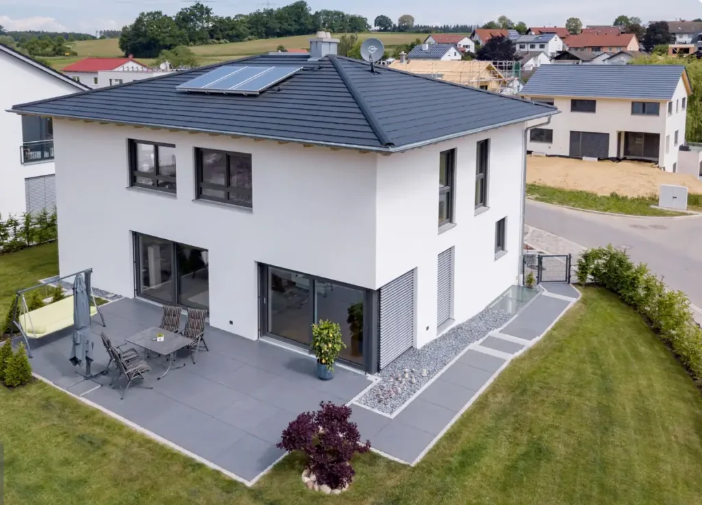 Modernes zweistöckiges weißes Haus mit Terrasse, Sonnenkollektoren und gepflegtem Rasen in einem Vorort.