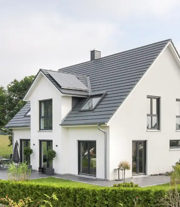 Modernes weißes zweigeschossiges Massivhaus bauen mit großen Fenstern, grauem Dach, Innenhof und Begrünung - nachhaltige Qualität inklusive.